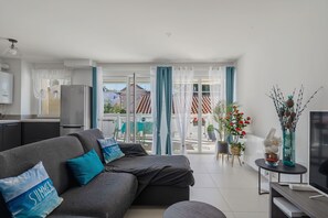 A modern living room with a sofa, a television, and a dining area with a table and chairs. - ArcachonAir plein centre dArcachon à 2 pas de la plage (Arcachon)