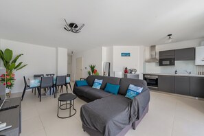 A modern living room with a grey sectional sofa, a dining area with a table and chairs, and a kitchen with grey cabinets and stainless steel appliances. - ArcachonAir plein centre dArcachon à 2 pas de la plage (Arcachon)