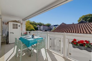 A balcony with a table set for two, white railings, and a view of neighboring houses. - ArcachonAir plein centre dArcachon à 2 pas de la plage (Arcachon)