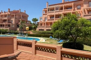 Ein Hotel mit mehreren Balkonen, einem Schwimmbad und einem gepflegten Garten.