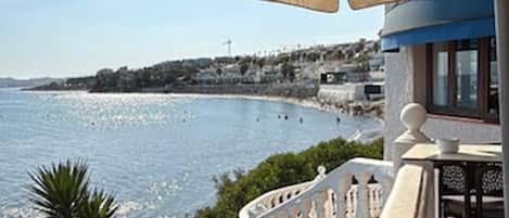 A seaside property with a balcony overlooking the sea, a white railing, and a clear view of the coastline.