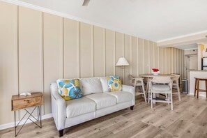 A living room with a sofa, a small table, and a lamp. - Romar Place 1105 (Orange Beach)