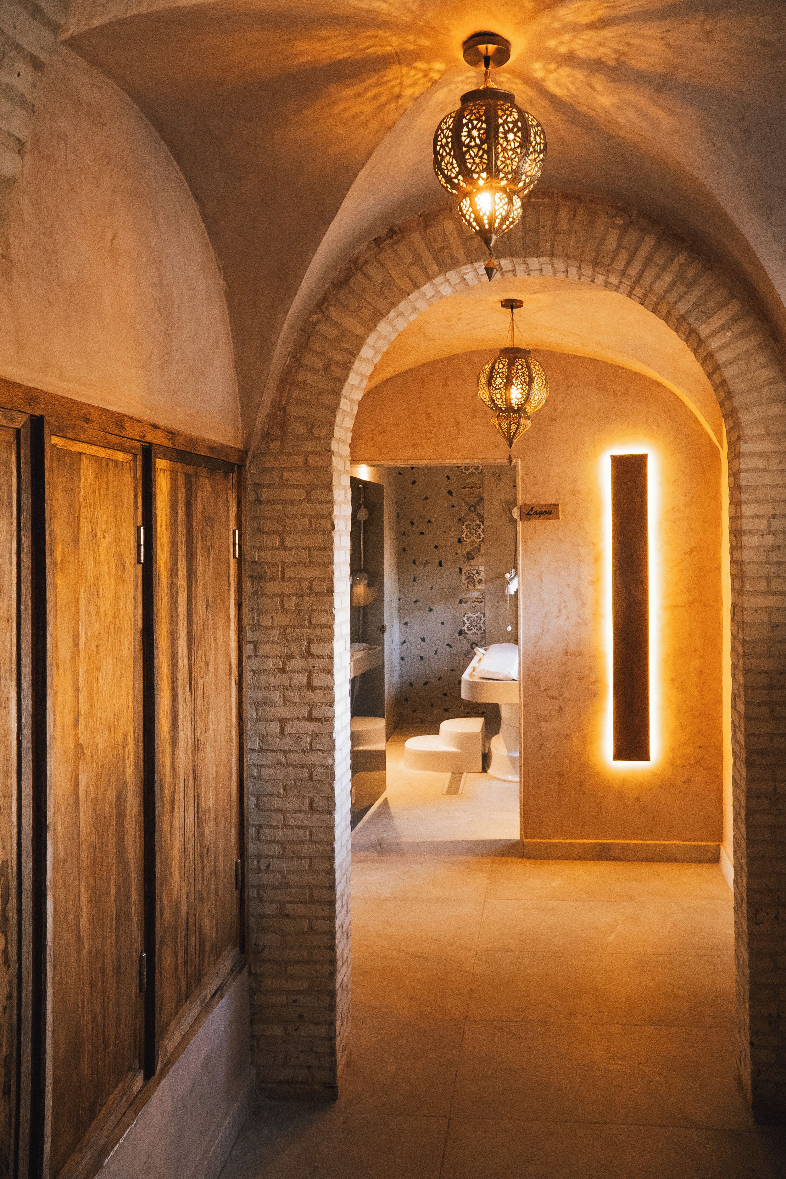 Un couloir aux plafonds en arc et une salle de bain moderne visible à travers une arche.