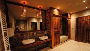 Une salle de bain avec deux lavabos, un miroir et une porte en bois.