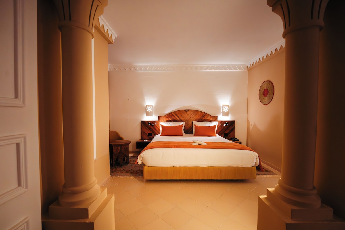 Habitación de hotel con una cama grande, dos mesitas de noche y un adorno en la pared.