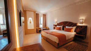 Une chambre d’hôtel avec un grand lit, une tête de lit en bois, un bureau et une chaise.