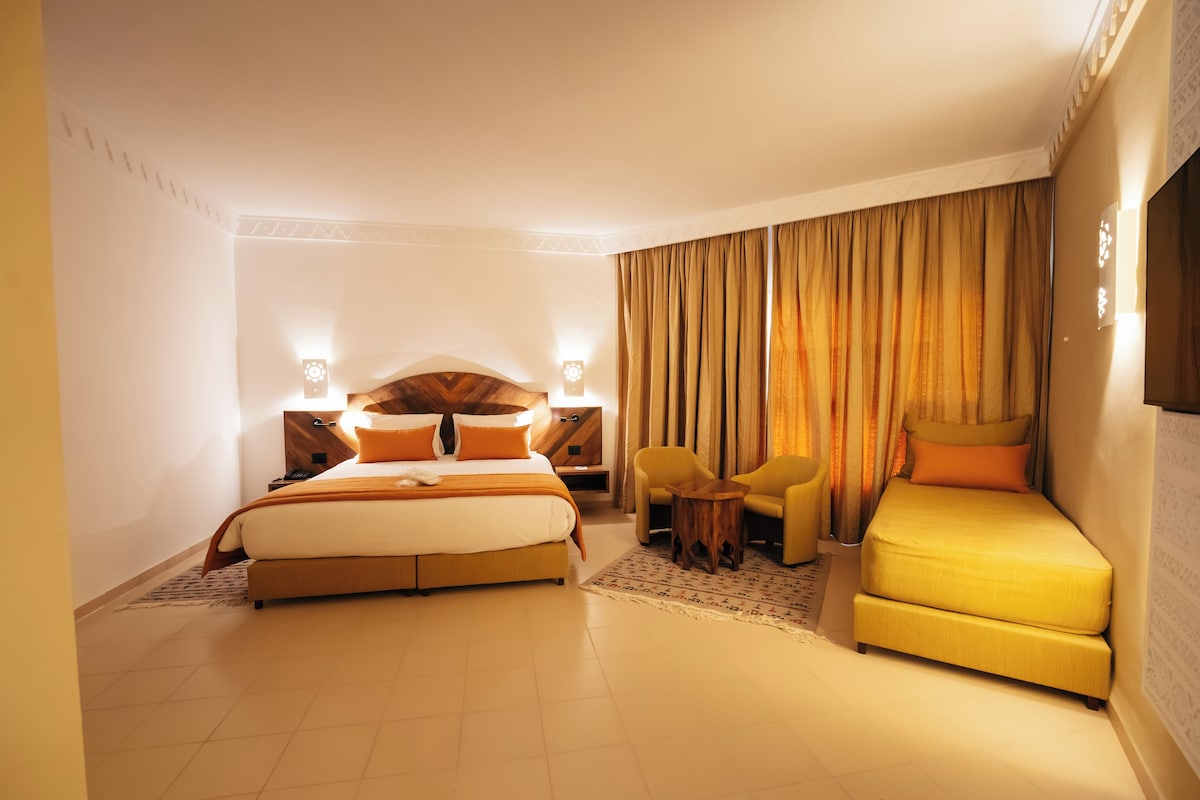 Una habitación de hotel con una cama, un sofá, una mesita y un televisor.