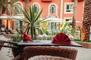 Una mesa dispuesta para comer, con servilleta roja, copas de cristal transparentes y una planta en maceta.