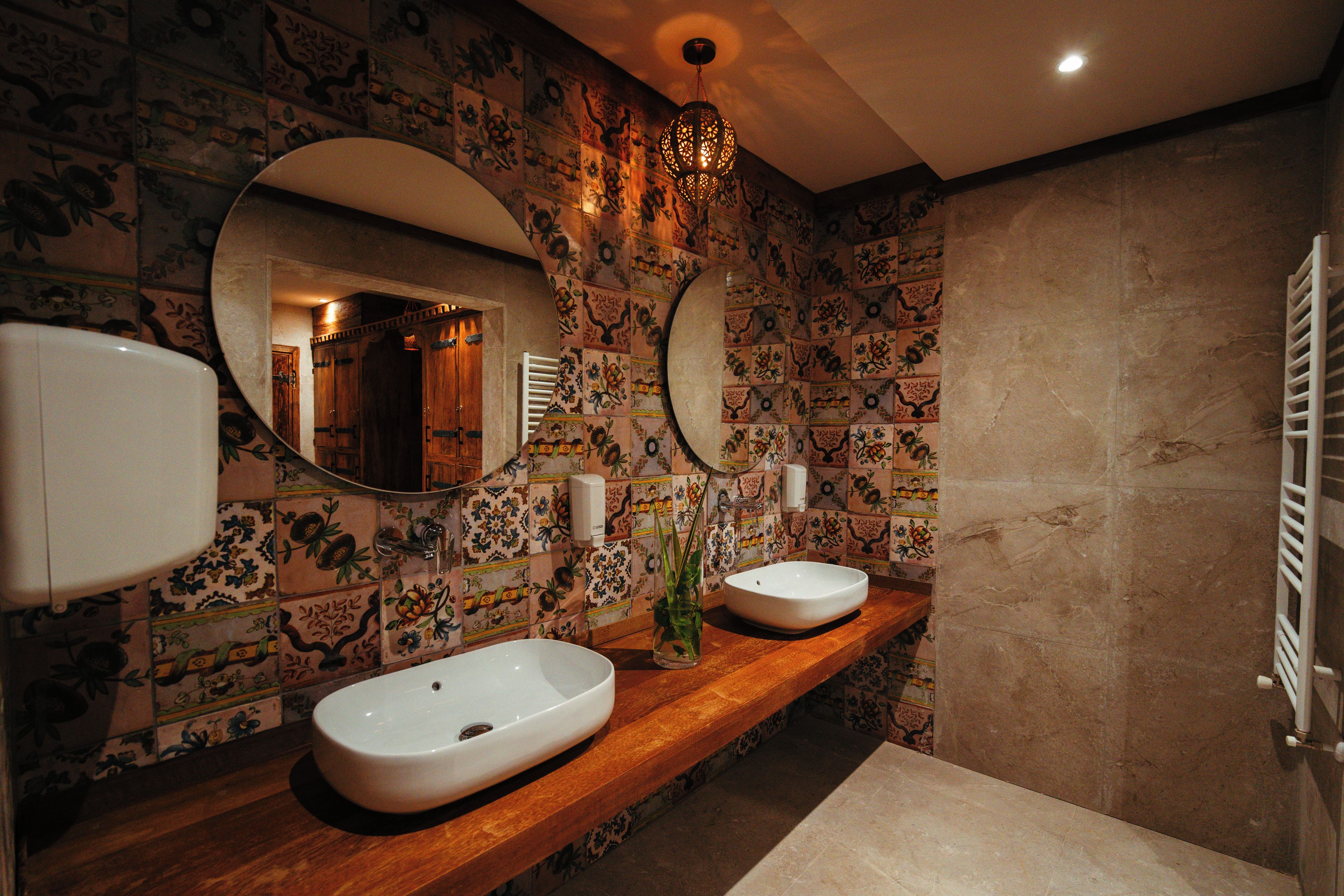 A bathroom with two sinks, a mirror, and a decorative light fixture.