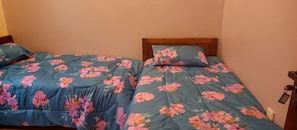 Une chambre avec deux lits, chacun agrémenté de draps à motifs floraux.