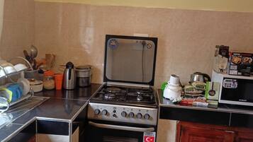 A compact kitchen with a stove, microwave, and various kitchen utensils.