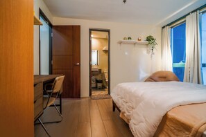 Ein Hotelzimmer mit einem Bett, einem Schreibtisch und einem Stuhl. Ein Badezimmer ist durch eine offene Tür sichtbar.