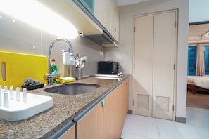A modern kitchen with a granite countertop, stainless steel sink, and a built-in microwave. - New! Roomy & Zen Wi-fi 350Mbps  Uptown BGC, One Uptown Residence (Taguig)