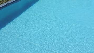 Ein klares, blaues Schwimmbecken mit gewölbter Kante und einer Rasenfläche im Hintergrund.