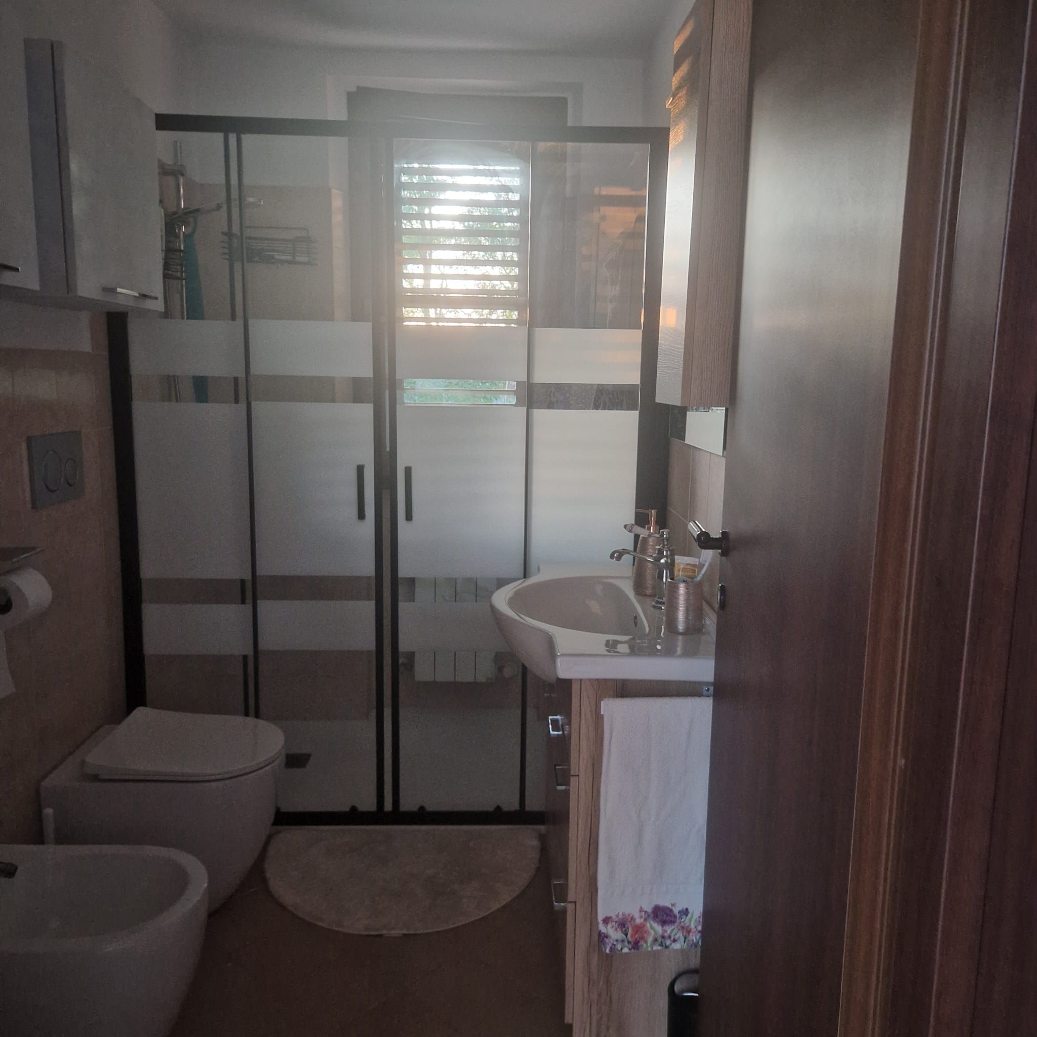 A bathroom with a toilet, bidet, and a glass-enclosed shower.