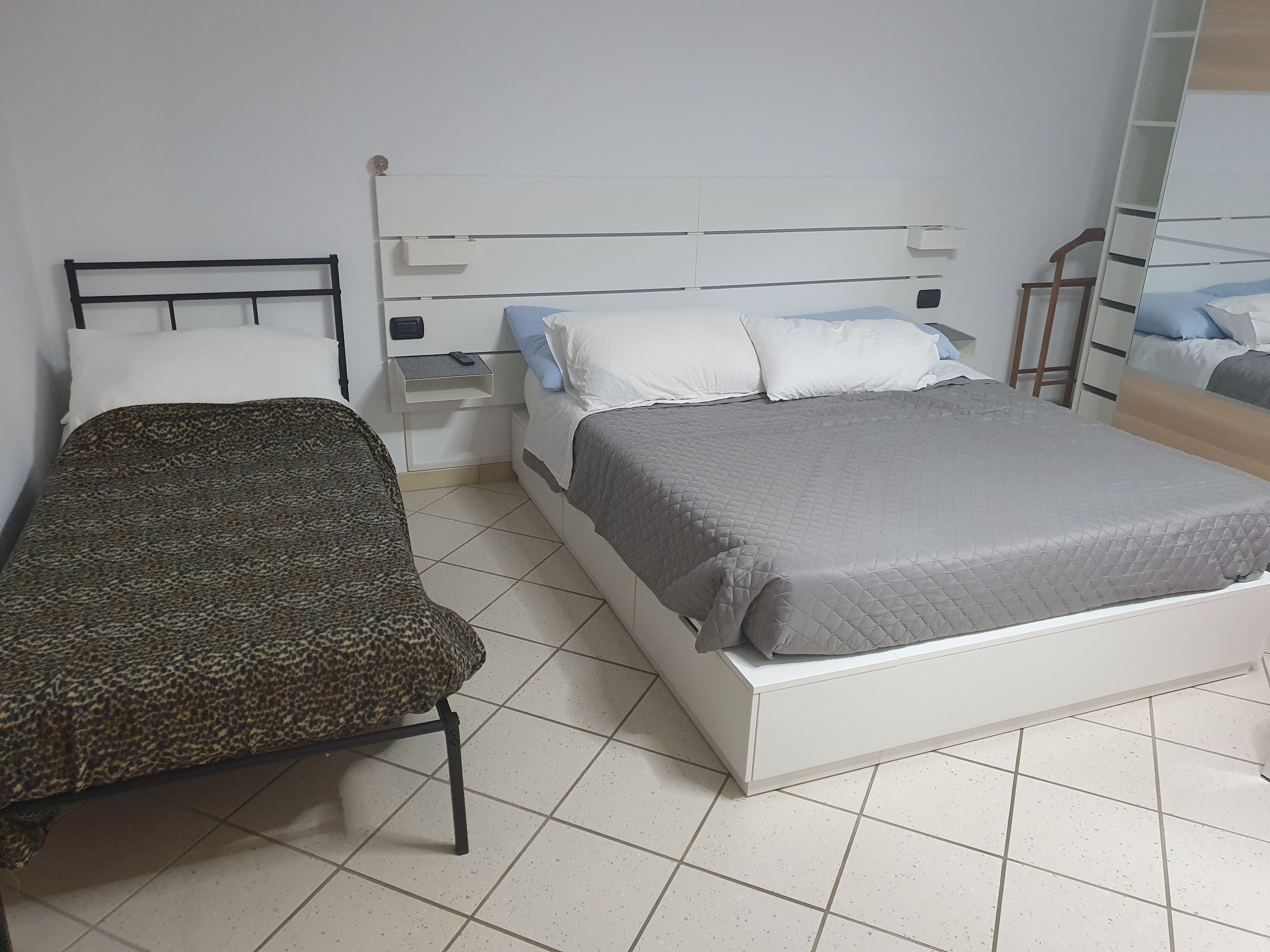 Ein Schlafzimmer mit Bett, Sessel, Nachttisch und Spiegel.