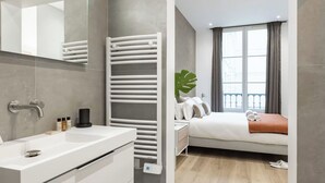 Een moderne badkamer met een wit wastafelmeubel, spiegel en handdoekrek.