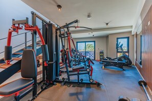 A gym with various exercise equipment, including a bench press, weight machines, and a rowing machine. - LUX 1BR House Pool Gym 7-Min Walk Palm Beach - Porta Al Sole 8 by Bocobay (Noord)
