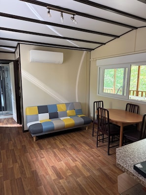 Ein modernes Interieur mit einer Couch, einem Esstisch, Stühlen und einer Klimaanlage.