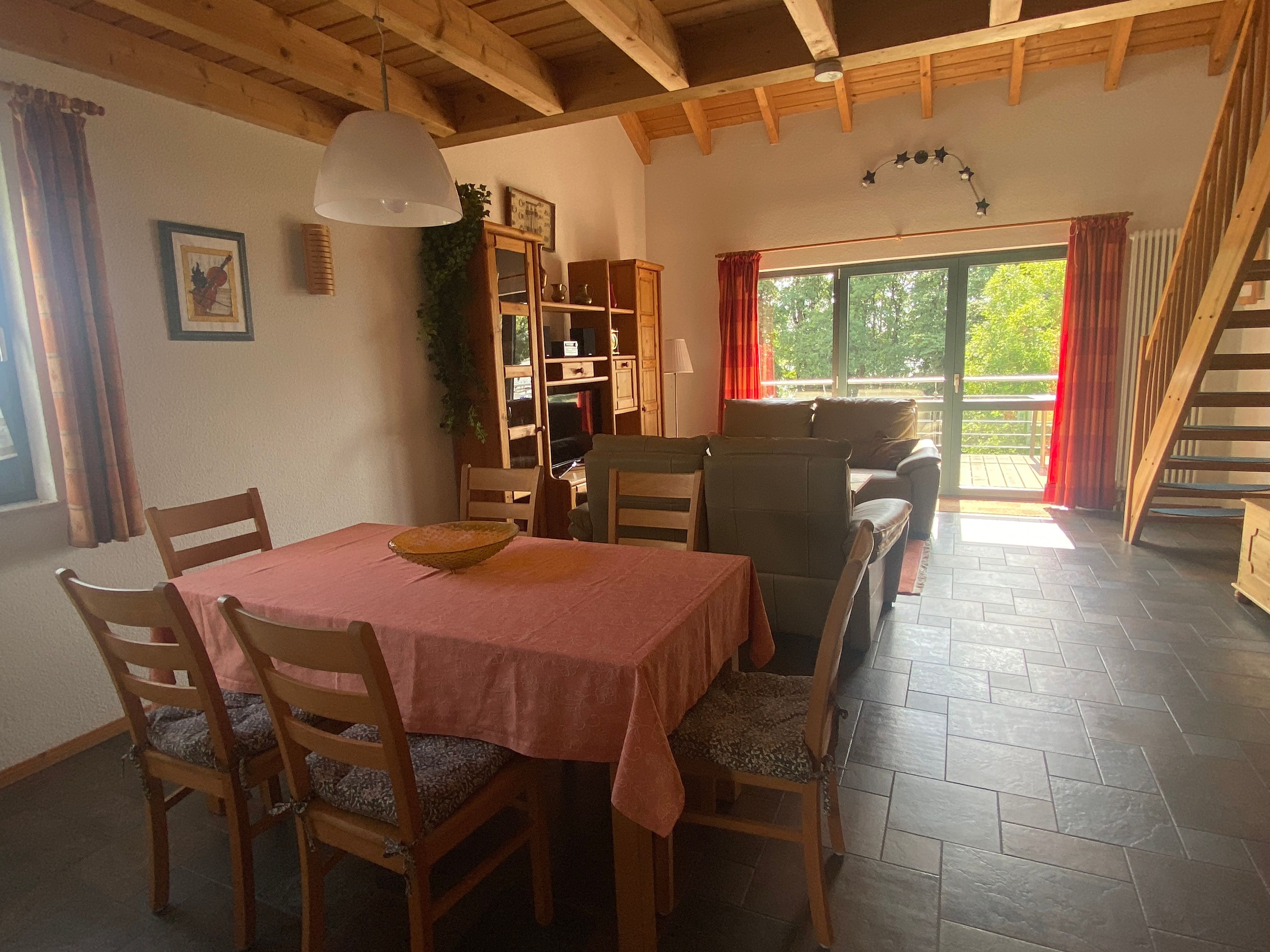 A dining area with a table and chairs, a wooden cabinet, and a staircase leading to an outdoor area.