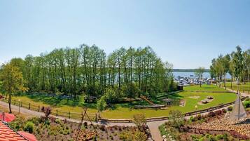 Vue d’une propriété au bord du lac, avec une terrasse en bois, un espace pique-nique et un quai pour bateaux.