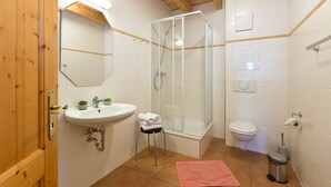 Un baño con lavamanos, inodoro, ducha y espejo.