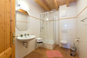 Une salle de bain avec un lavabo, des toilettes, une douche et un miroir.