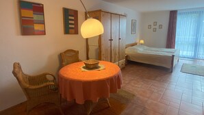 Una habitación con una mesa redonda, una cama, un armario y una ventana.
