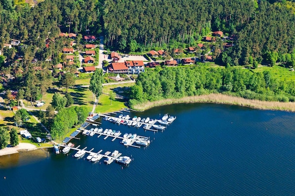 Vue aérienne d’une propriété au bord du lac, avec un port de plaisance, des maisons et une forêt dense.
