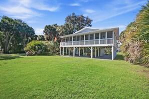 A two-story house with a covered porch and a lawn. - Edisto Escape (Edisto Island)