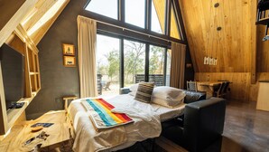 A bedroom with a bed, a desk, a chair, and a dining area. - A quiet A-frame escape in the Texas countryside, made for slowing down. (Ledbetter)