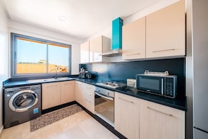 A compact kitchen with a washing machine, microwave, and a window with a view. - Modern Escape in Gueliz |Terrasse| View | Parking (Marrakesh)
