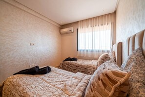 A hotel room with two beds, a window with sheer curtains, and an air conditioning unit on the wall. - Modern Escape in Gueliz |Terrasse| View | Parking (Marrakesh)