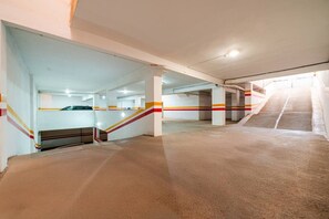 An indoor parking garage with multiple levels, concrete floors, and white walls with red and yellow stripes. - Modern Escape in Gueliz |Terrasse| View | Parking (Marrakesh)