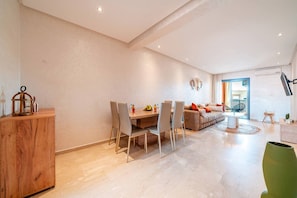 A modern living room with a dining area, a sofa, and a TV mounted on the wall. - Modern Escape in Gueliz |Terrasse| View | Parking (Marrakesh)