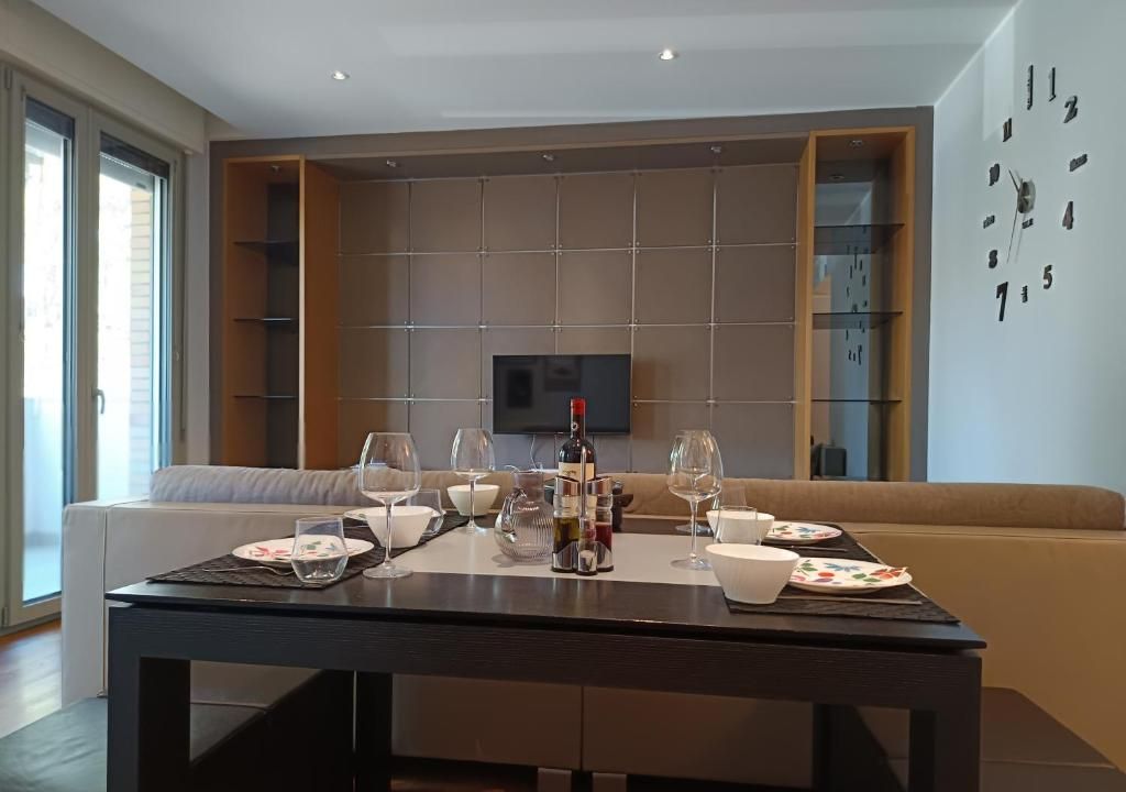 Un soggiorno moderno con un divano, un tavolo da pranzo per quattro persone e una televisione a parete.