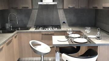 Una cucina moderna con piano cottura a gas, lavello in acciaio inossidabile e sgabelli da bar.