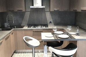 A modern kitchen with a gas stove, stainless steel sink, and bar stools. - As cozy as your own home!  Comfort and genuine hospitality in the heart of Ravenna. (Ravenna)