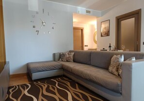 A modern living room with a sofa, a small table, and a clock on the wall. - As cozy as your own home!  Comfort and genuine hospitality in the heart of Ravenna. (Ravenna)