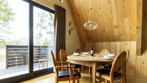 A dining area with a wooden table, chairs, and a wine bottle. - A quiet A-frame escape in the Texas countryside, made for slowing down. (Ledbetter)