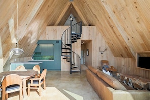Bathed in the amber glow of golden hour, the cabin’s interior opens onto a sweeping view of Legacy Lake