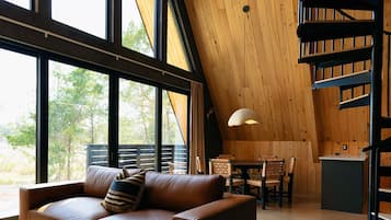 Ein geräumiges Loft mit hoher Decke, einer geschwungenen Treppe, einer Ledersofa und einem Essbereich mit viel Tageslicht durch große Fenster.