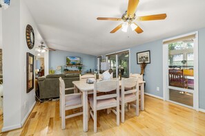 A dining area with a wooden table and chairs, a ceiling fan, and a television on a stand. - Private Beach, Lakefront, Dock, Kayaks, Canoe, Fireplace, Grill (Macon)