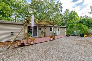 A single-story mobile home with a covered porch, a well-maintained garden, and a gravel driveway. - Private Beach, Lakefront, Dock, Kayaks, Canoe, Fireplace, Grill (Macon)