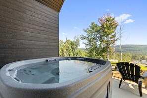 A hot tub on a patio with a view of trees and hills. - Spa, Nature & Mountain | Chalet des montagnes (Saint-Côme)