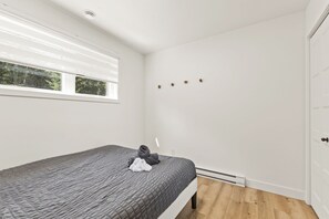 A bedroom with a bed, a window, a door, and a wall-mounted heater. - Spa, Nature & Mountain | Chalet des montagnes (Saint-Côme)