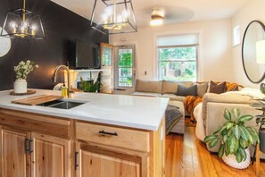 Une cuisine moderne dotée d’un grand îlot central, de meubles en bois et de luminaires suspendus.