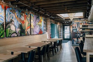An interior with graffiti art on the walls, wooden tables, and chairs. - Trendy 1BR w/Office & Wellness Rm l Sunnyside (Denver)