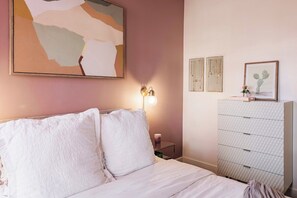 Een slaapkamer met een bed, een dressoir en wanddecoratie.