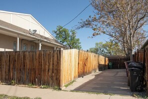 A residential area with a wooden fence, a parked bicycle, and a trash bin. - Trendy 1BR w/Office & Wellness Rm l Sunnyside (Denver)